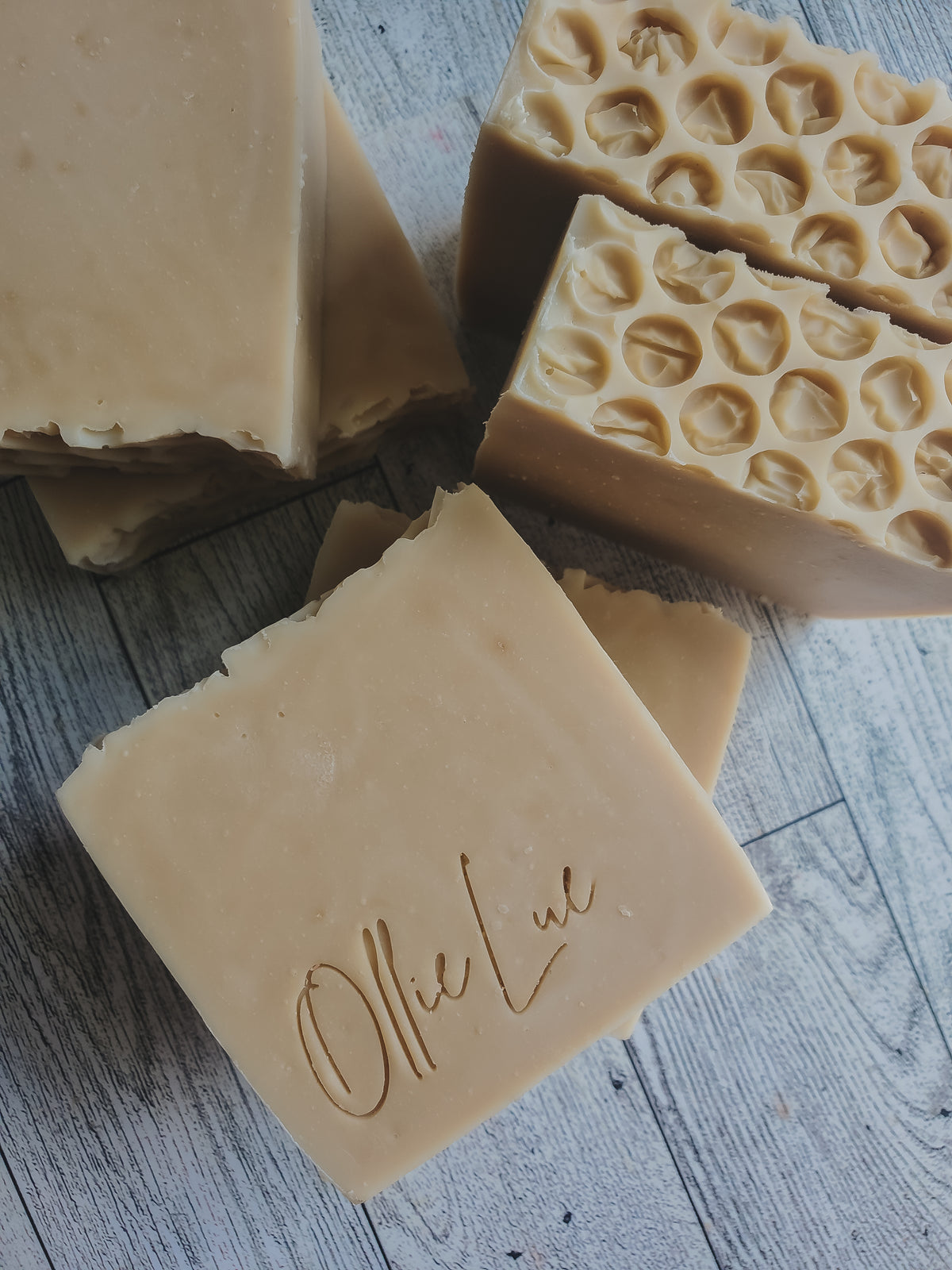 Four soap bars with different textures on gray background featuring the brand 'Ollie Lue'.