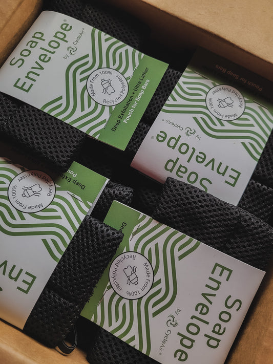 Three black soap envelopes with green and white geometric patterns, placed in a cardboard box with 'SOAP ENVELOPE' text on the top.