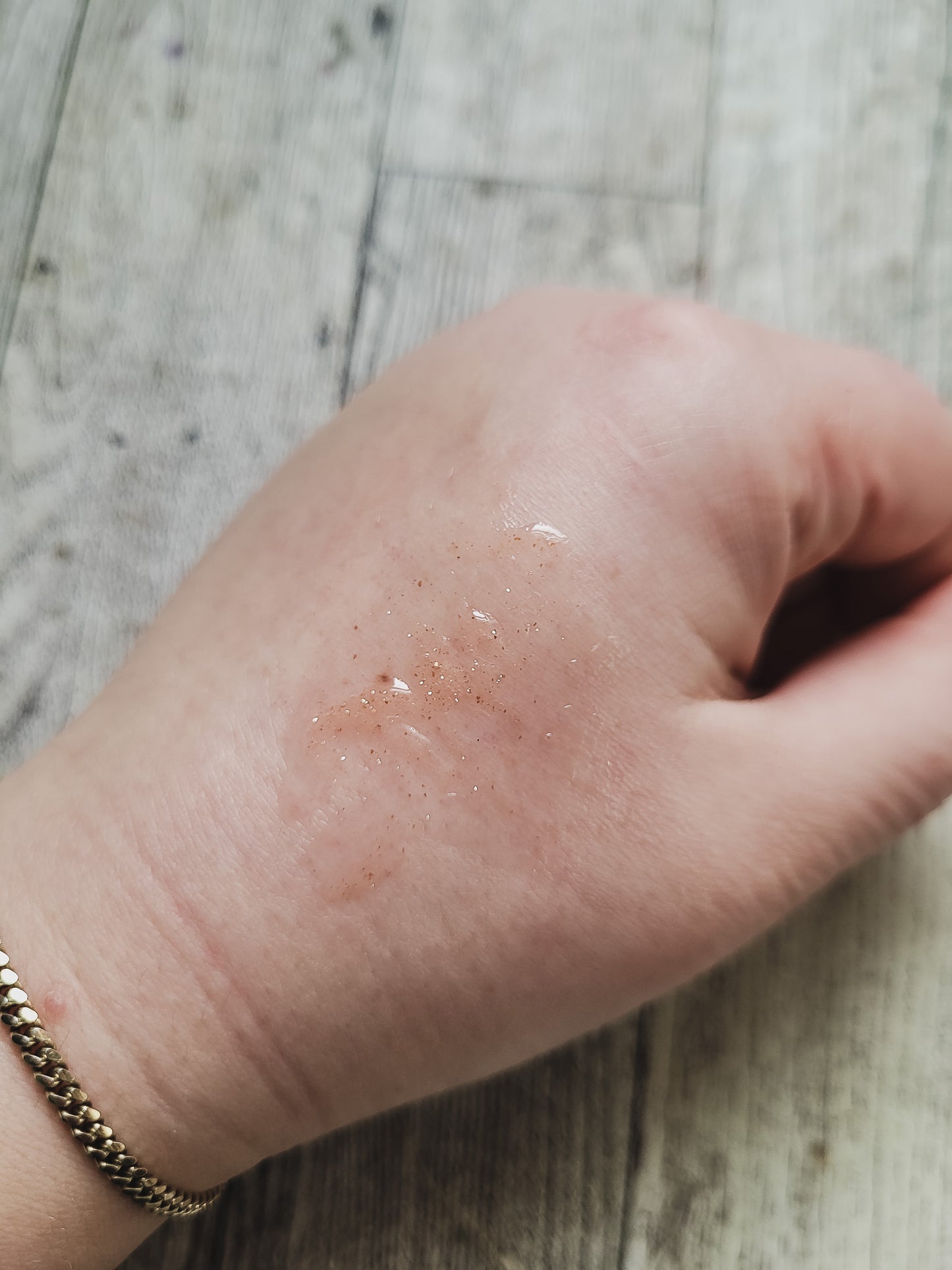 shimmer gloss shown on hand on a wooden background