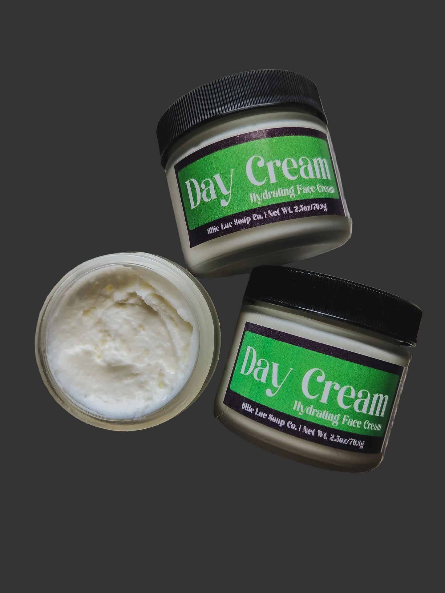 Two jars of Day Cream with a black lid on a dark background