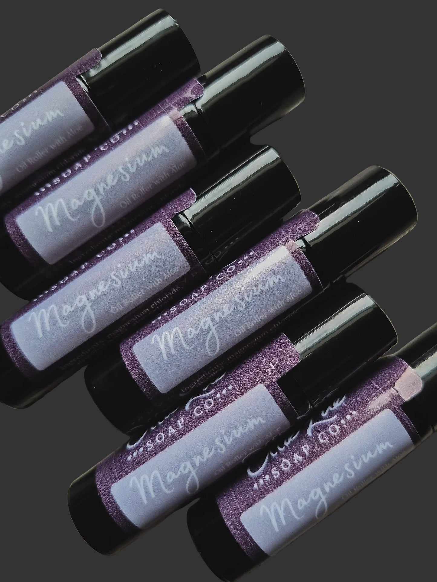 Roll-on bottles labeled 'Magnesium' from Soap Co. on a dark background