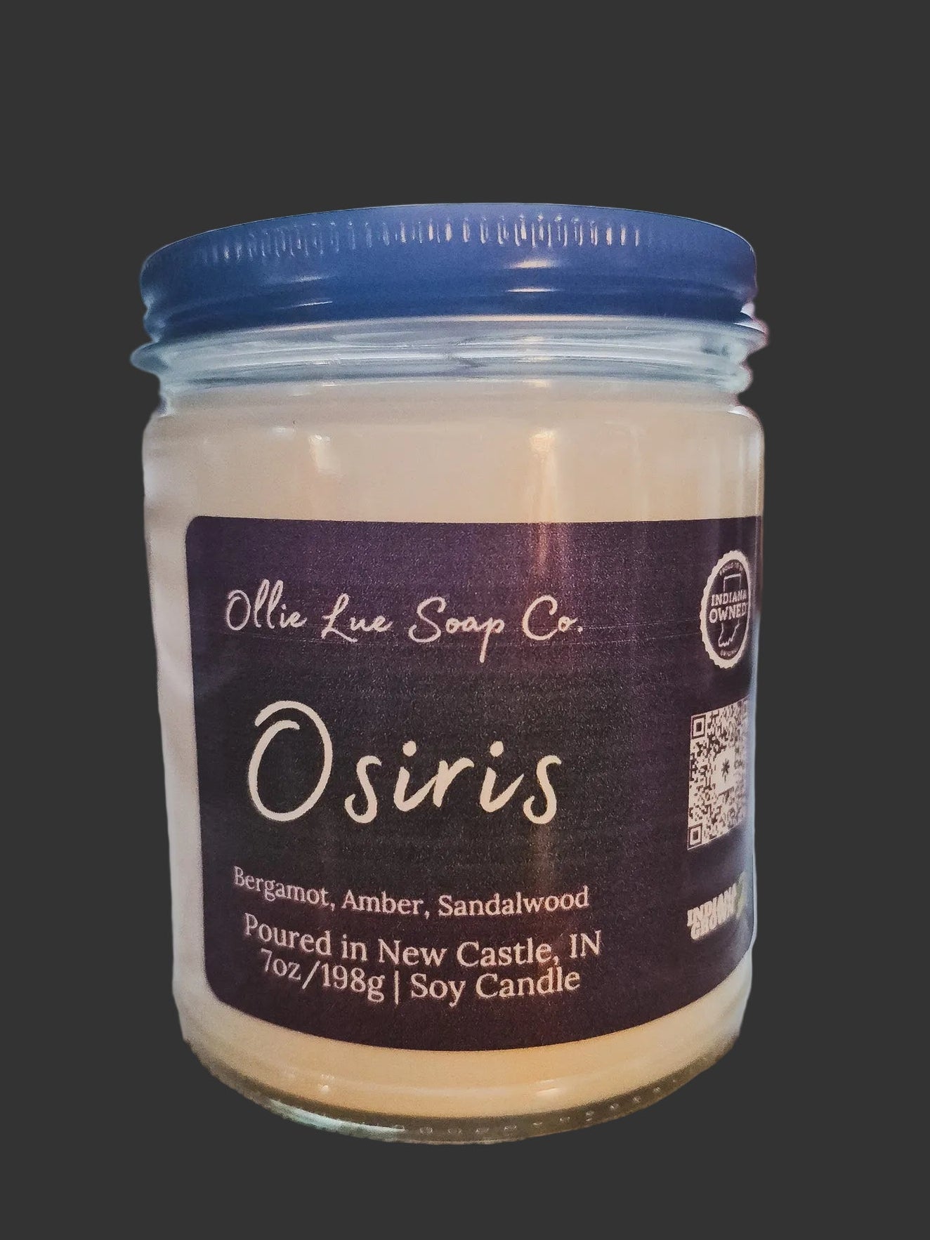 Jar of 'Osiris' candle from Ollie Lue Soap Co. with a dark label on a black background