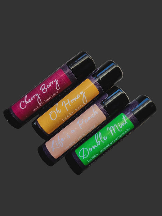 Four lip balm tubes with colorful labels on a wooden surface