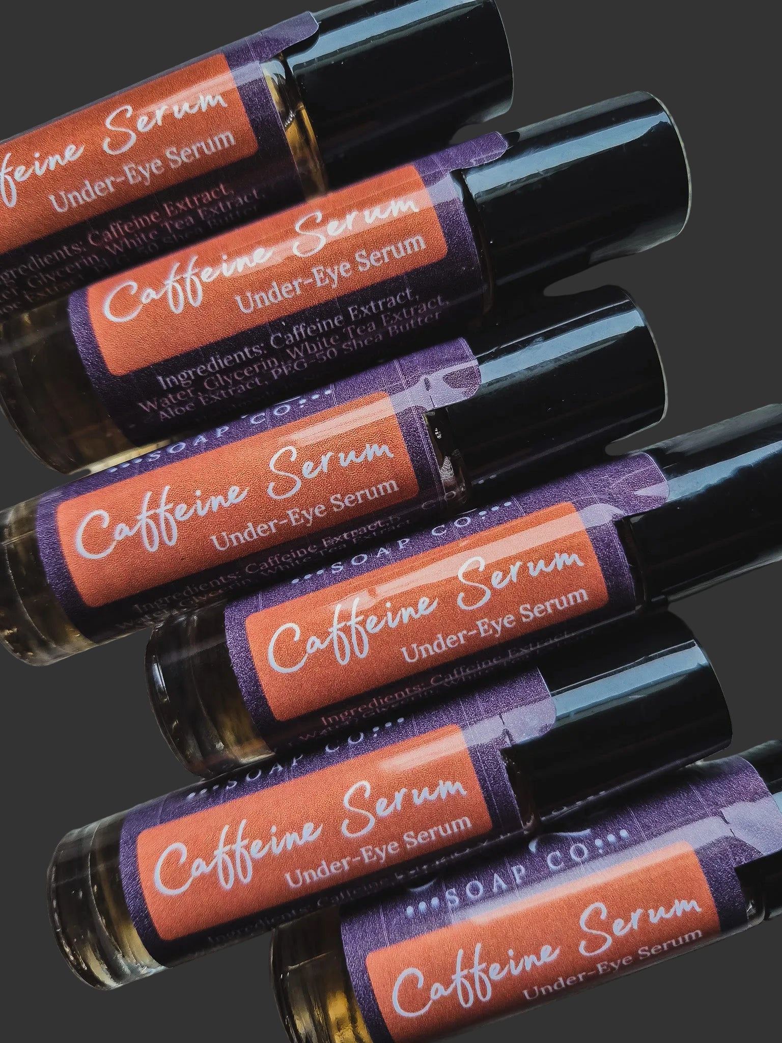 Roll-on bottles of caffeine serum under-eye serum with colorful labels on a dark background