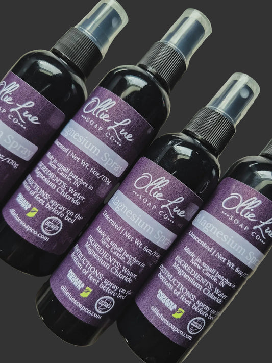 Row of Ollie Lue Soap Co. magnesium spray bottles on a dark background