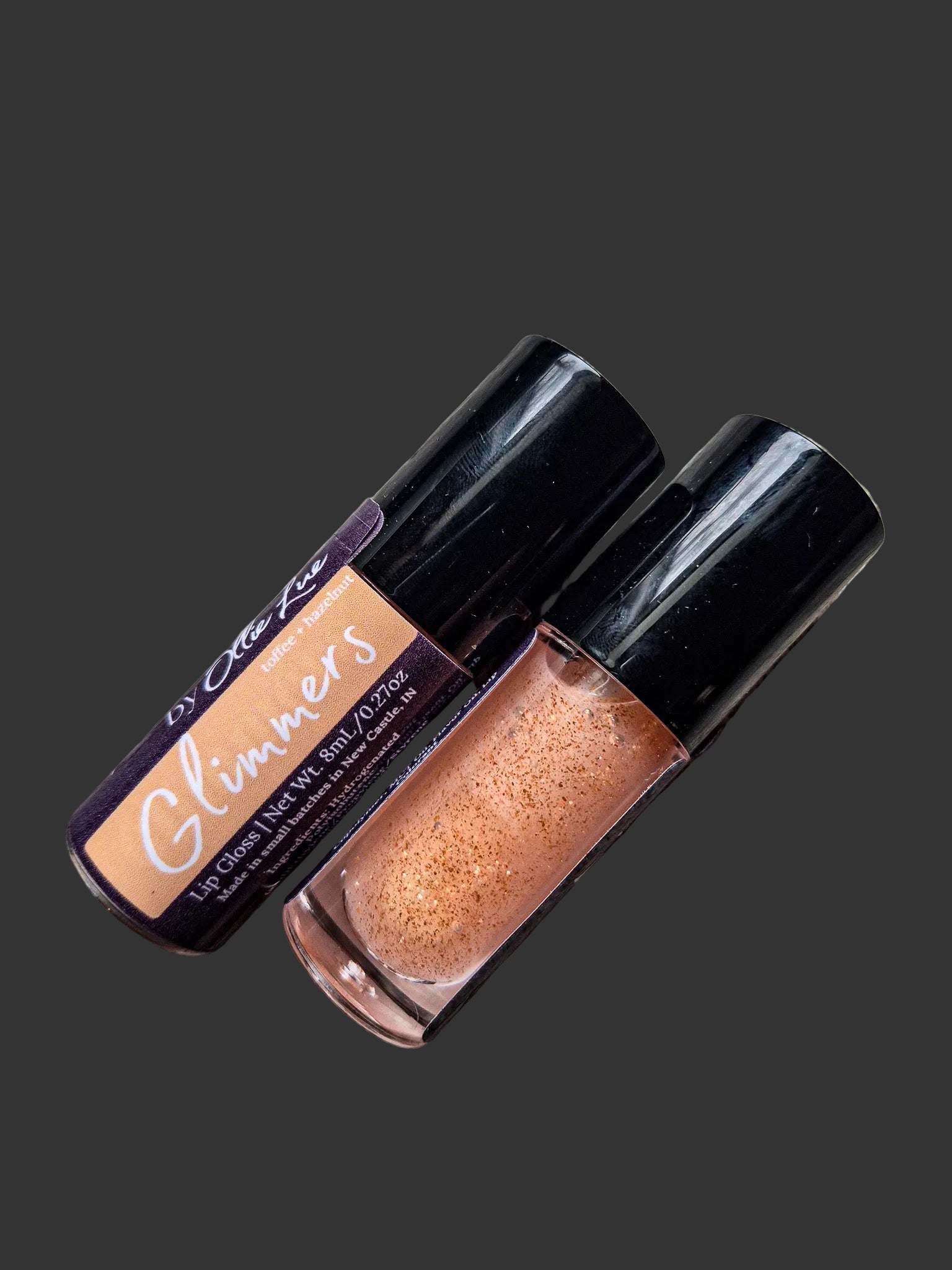 Two lip glosses with 'Glimmers' label on a dark background