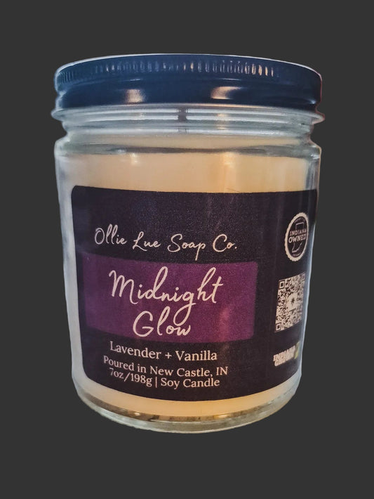 Jar of candle labeled 'Midnight Glow' by Ollie Lue Soap Co. on a dark background