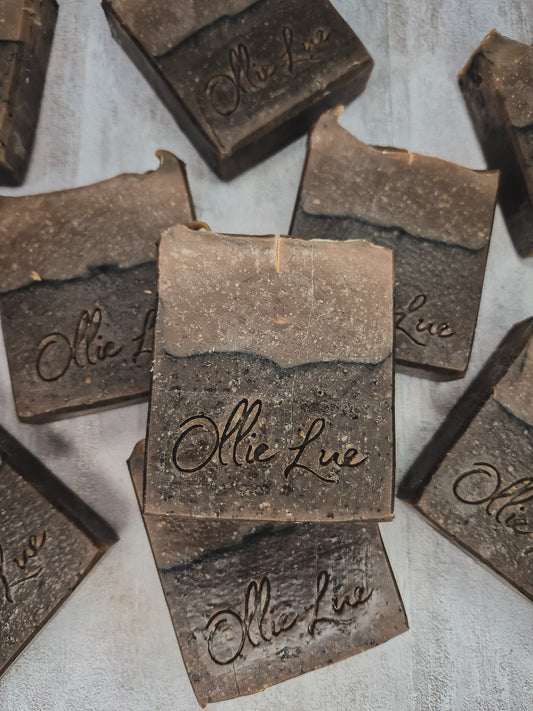 Several rustic rectangular bars of soap with the brand name 'Ollie Lue' embossed on the front, arranged on a light textured surface.
