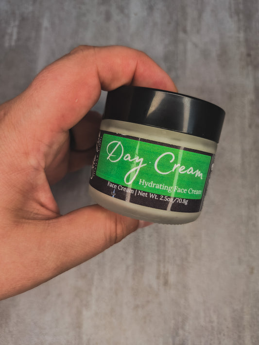 A hand holding a jar of Day Cream Hydrating Face Cream against a textured gray concrete background.